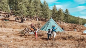Mongolia reindeer herder tour Tsaatan kids riding reindeer Taiga camp