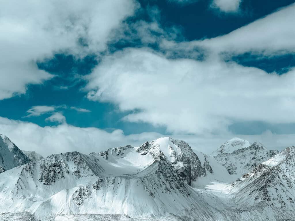 Snow-covered mountains under a blue sky in the Altai region of Mongolia