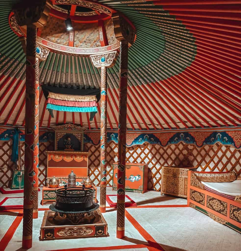 Interior of a traditional Mongolian yurt with painted wooden beams and furniture