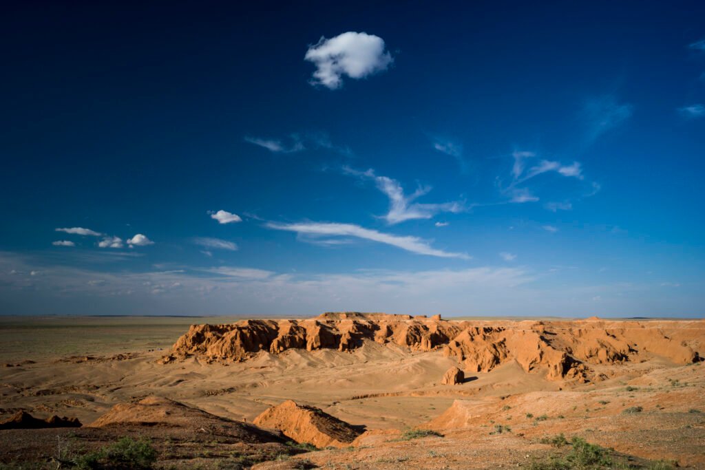 Bayanzag Flaming Cliffs red sandstone formations in the Gobi Desert of Mongolia under a blue sky.