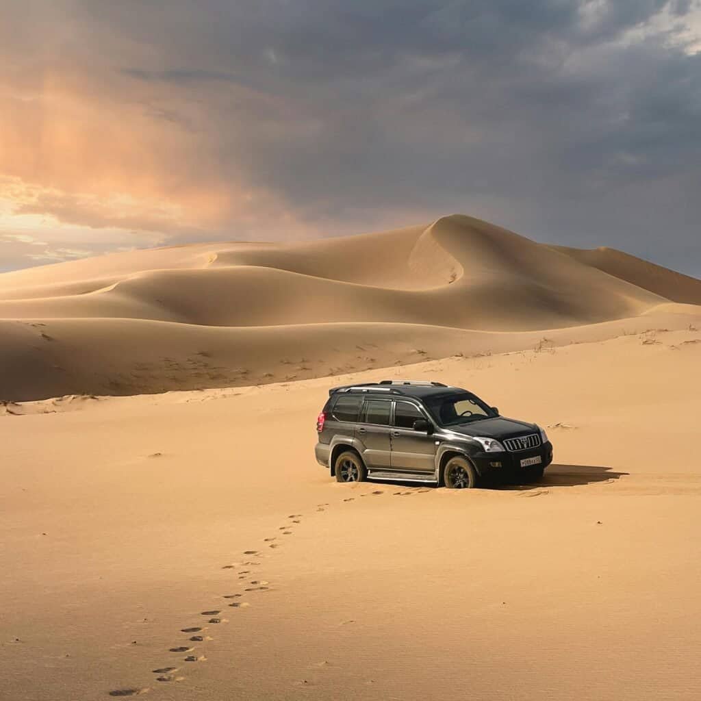 4x4 car driving across Gobi Desert sand dunes Mongolia